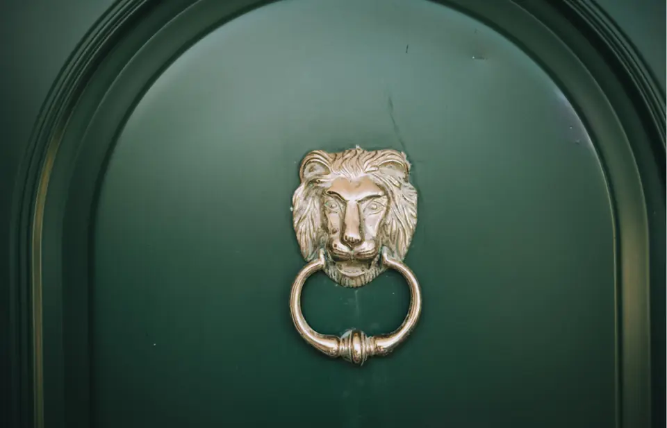 A green front door with a brass lion knocker