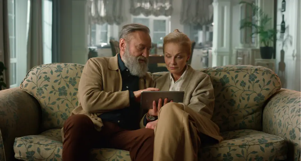 An older couple engaged together in a snug sitting room